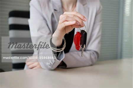 Female financial advisor holding a car key in an office