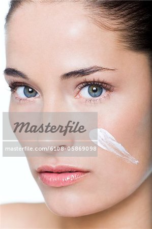 Young woman with moisturizer on her cheek