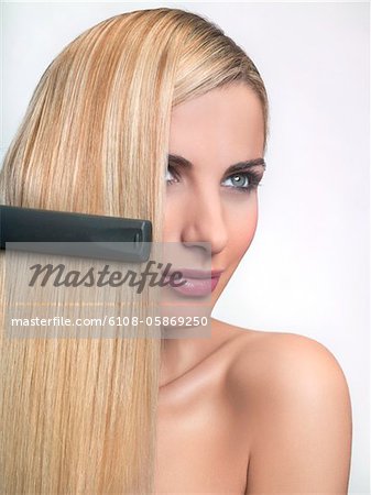 Young woman using hair straighteners