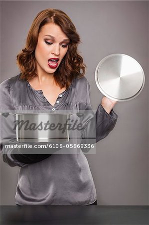 Young woman looking at content of stew pot