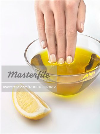 Close-up of woman's hand in bowl of olive oil Close-up of woman's hand in bowl of olive oil