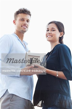 Portrait of a young couple holding small model house