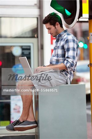 Man using a laptop near traffic light