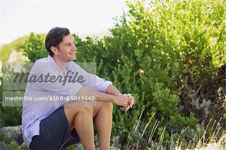 Mid adult man sitting on a rock in a garden