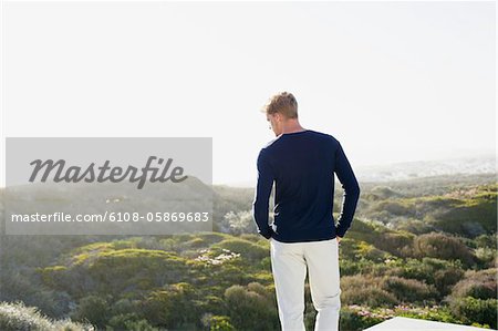 Rear view of a young man looking at view from the terrace of a house