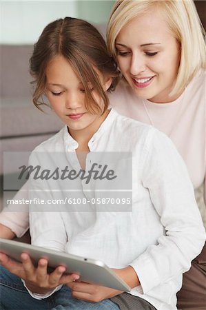 Woman assisting her daughter in using a digital tablet