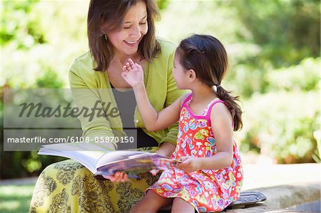 Woman and her granddaughter looking at each other while holding a book in hand