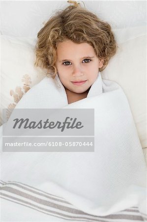 Portrait of a cute little girl wrapped in a white towel