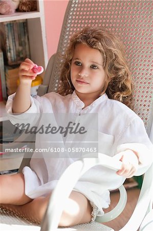 Cute little girl playing with a toy while sitting on rocking chair