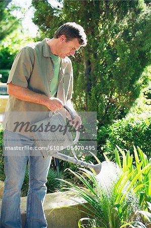 Mature man watering plants in a garden