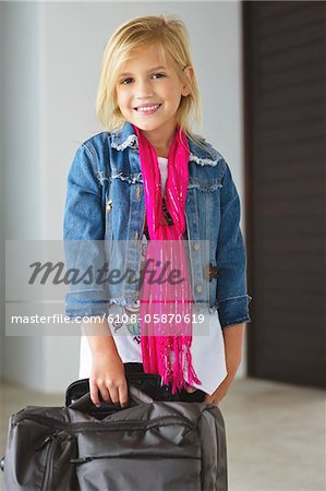 Portrait of a smiling girl standing near her luggage