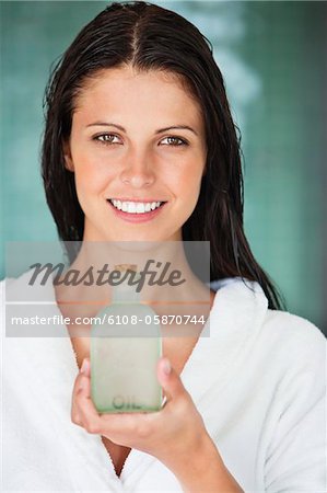 Portrait of a woman holding a bottle of aromatherapy oil and smiling