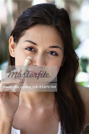 Portrait of a beautiful young woman applying make-up