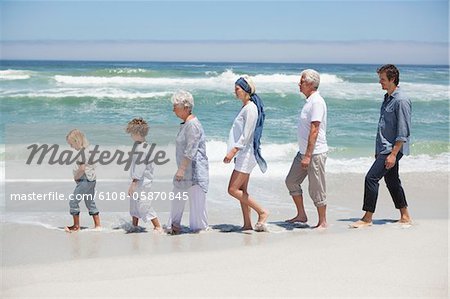Family walking in a row at beautiful beach with kids