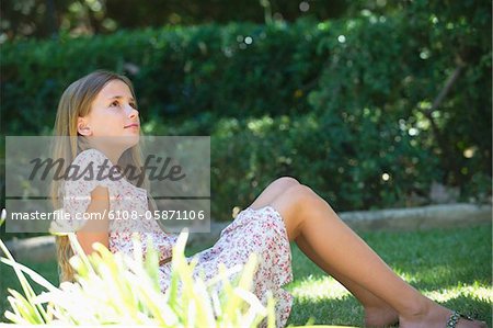 Contemplative little girl looking up in garden