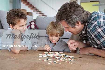 Man playing pick up sticks with his sons