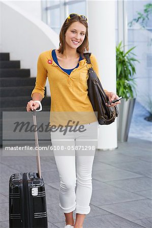 Portrait of a woman holding a mobile phone and a trolley bag