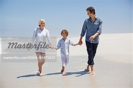 Couple walking on the beach with their son