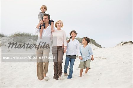 Couple walking on the beach with their children