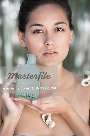 Portrait of a beautiful young woman holding bottle of olive oil