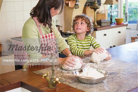 Grandmother and little boy kneading dough at kitchen