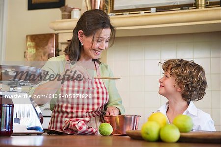 Grandmother and little boy cooking food at kitchen