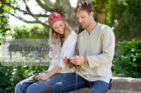 Young couple knitting together and smiling