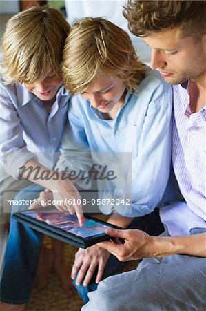 Man and two little boy looking at digital tablet