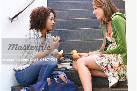 Side profile of university students eating food on stairs in university