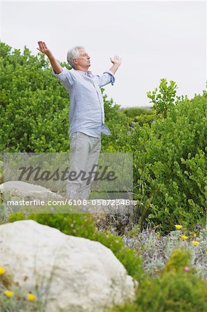 Senior man standing with his arm outstretched in a garden