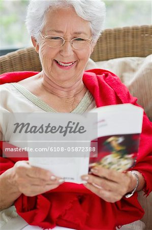 Senior woman reading a magazine and smiling