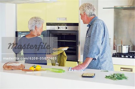Senior couple baking food in an oven