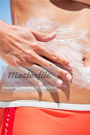 Close-up of a woman applying suntan lotion on her body