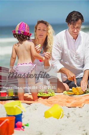 Woman feeding fruits to her daughter on the beach