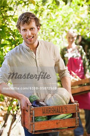 Smiling man holding a crate of vegetables