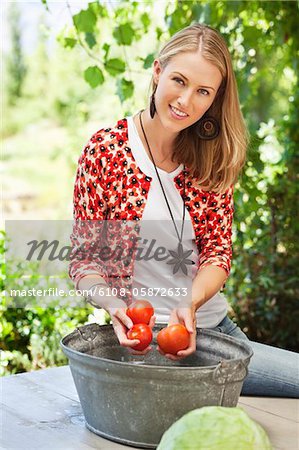 Portrait of a smiling woman washing tomatoes