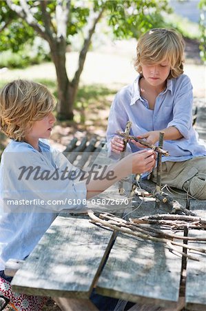 Children making frame of driftwood outdoors
