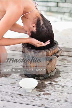 Woman washing hair into a bucket