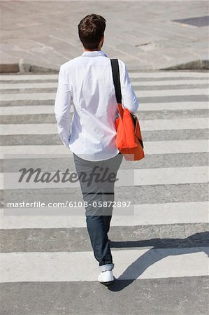 Rear view of a man walking in crosswalk, Paris, Ile-de-France, France