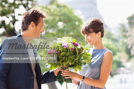 Man giving a bouquet of flowers to a woman with the Eiffel Tower in the background, Paris, Ile-de-France, France