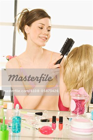 Young smiling woman in underwear brushing wig