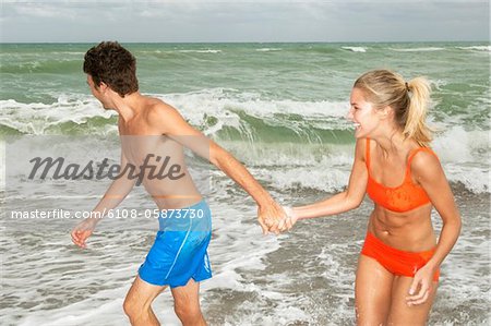 Couple holding hands and walking on the beach