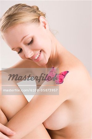 Woman looking at a butterfly on her shoulder and smiling