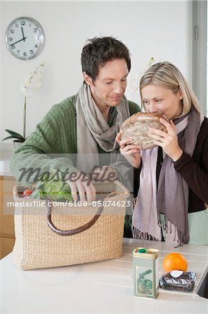 Woman smelling a loaf of bread with her husband standing beside her