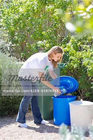 Woman throwing water bottles in garbage bin