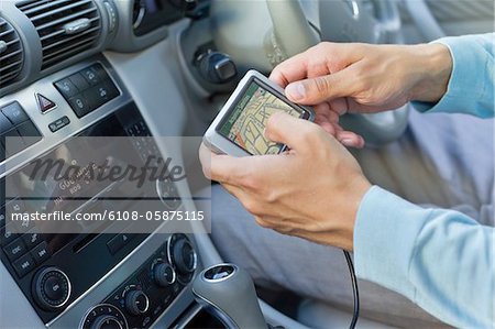 Close-up of human hand using GPS navigation system in car