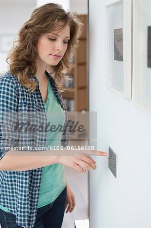 Woman pressing light switch on a wall