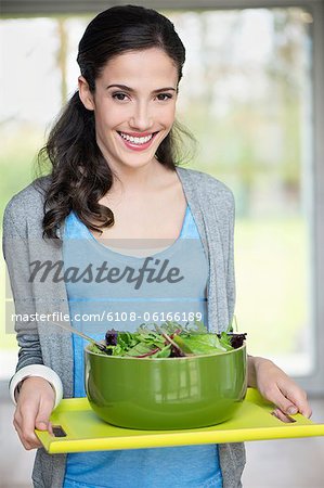 Woman carrying a bowl of salad on a tray