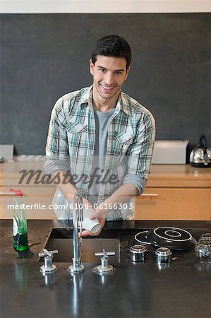 Portrait of a man washing dishes in the kitchen
