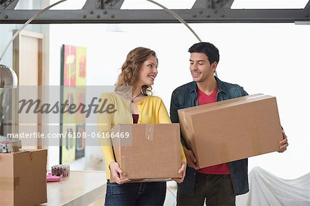 Couple carrying cardboard boxes and smiling